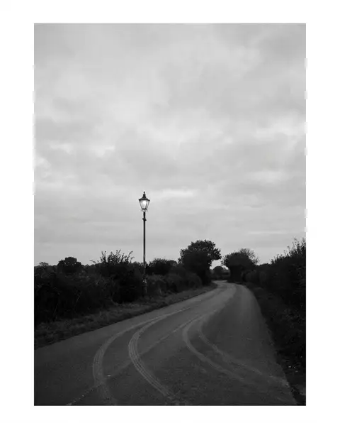 Empty night road with tire skid marks under a street light