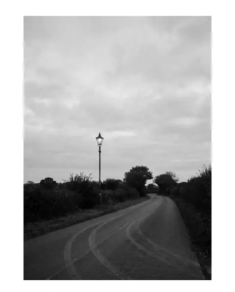 Empty night road with tire skid marks under a street light