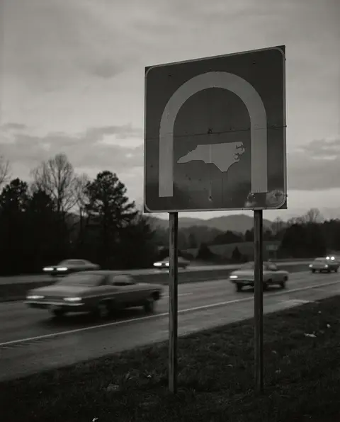 Welcome to North Carolina highway sign beside an interstate at dusk