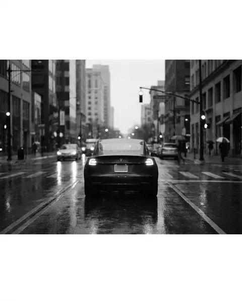 Car stopped at a stoplight with hazard lights on a wet street