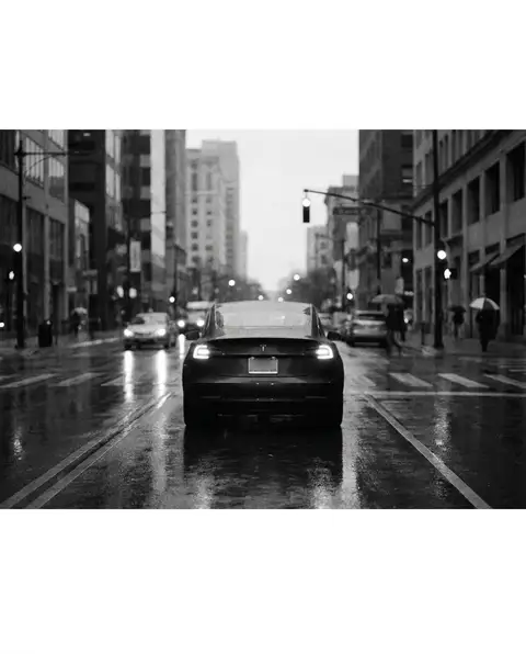 Car stopped at a stoplight with hazard lights on a wet street
